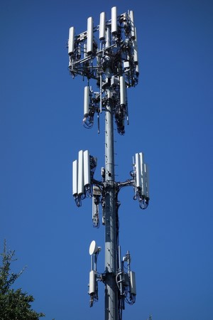 Cell tower with multiple antennas against a clear blue sky