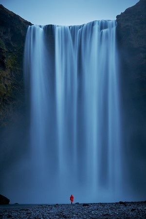 Person in red coat at Skogafoss waterfall
