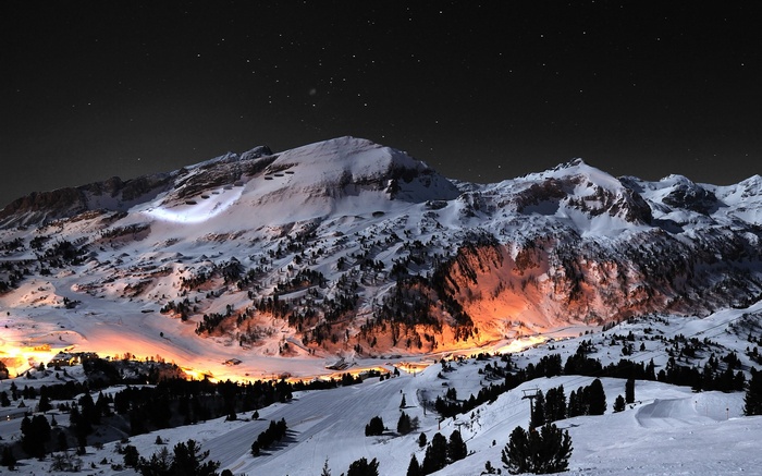 Snowy mountains at night with village lights