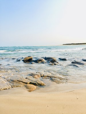 Rocks on a sandy beach with ocean waves
