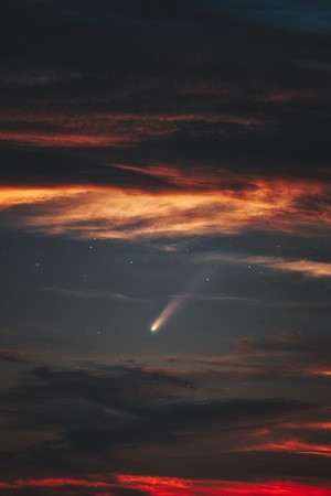 Comet in the night sky with clouds and stars