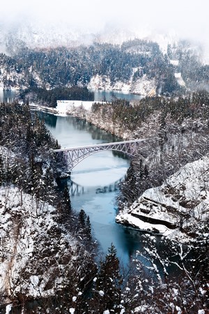 Snowy valley with a bridge over a river in Japan