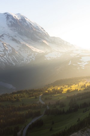 Snowy mountain range with a winding road through a forest
