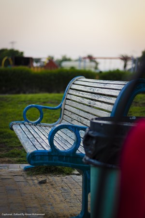 Park bench with playground in the background at sunset