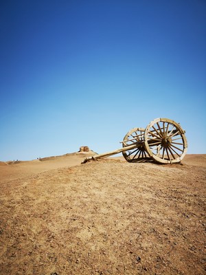 Ancient wooden cart on a desert hill under blue sky