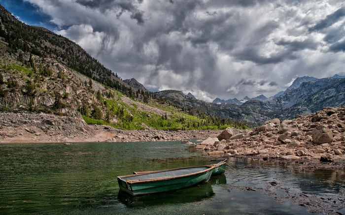 Two boats on a lake with mountains and stormy clouds