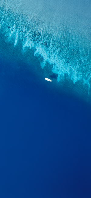 Aerial view of a white boat on blue ocean water near coral reef