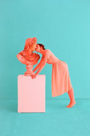 Woman kissing a coral bust on a pedestal