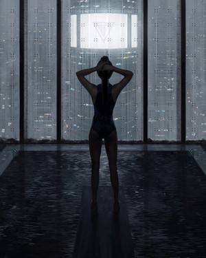 Woman in swimsuit by indoor pool with city view