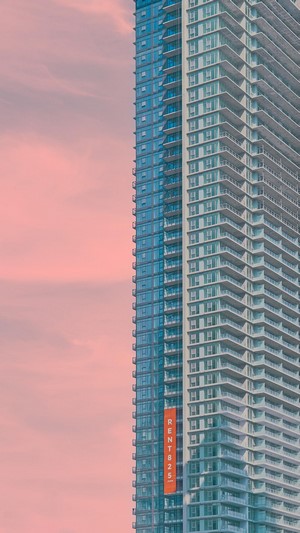 Skyscraper with RENTB25 banner against pink sky
