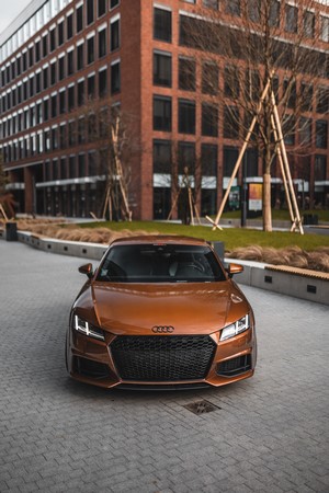Orange Audi TT sports car parked in front of a modern building