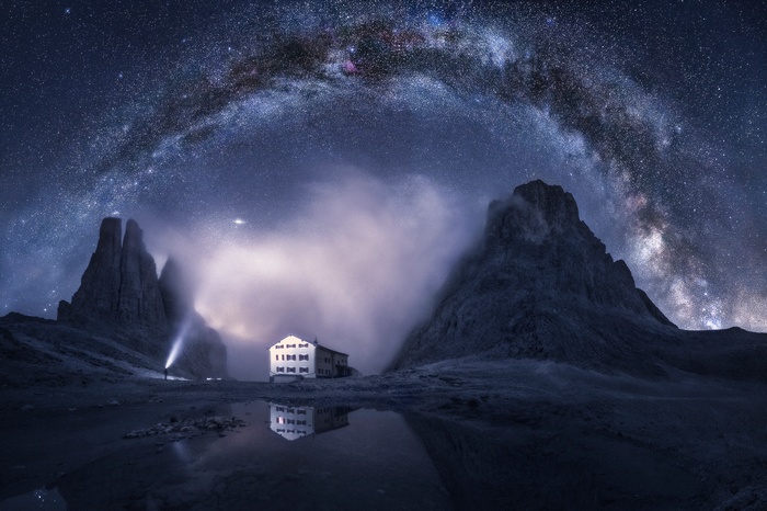 Milky Way over a mountain hut and rocky peaks