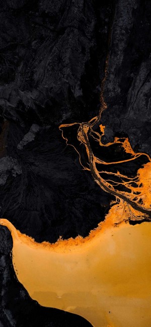 Aerial view of dark volcanic rock and orange river delta