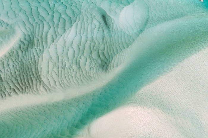 Aerial view of sand dunes and turquoise water