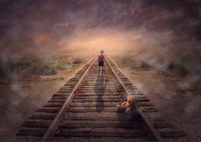 Boy and teddy bear on train tracks in fog