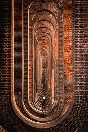Person standing under a brick viaduct with arches