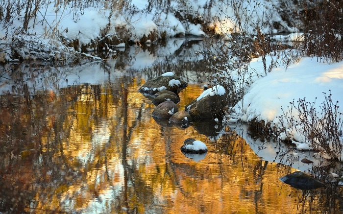 Winter stream with reflections and snow-covered banks