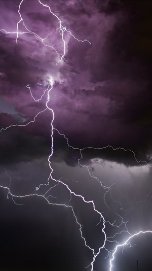 Lightning strikes through dark purple storm clouds
