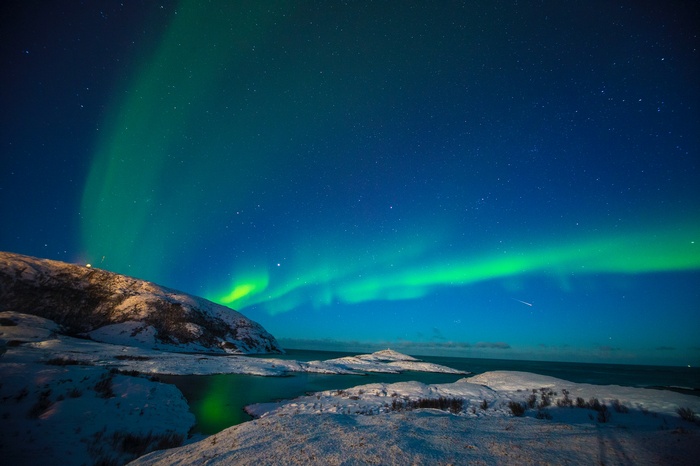 Aurora Borealis over snowy landscape in Norway