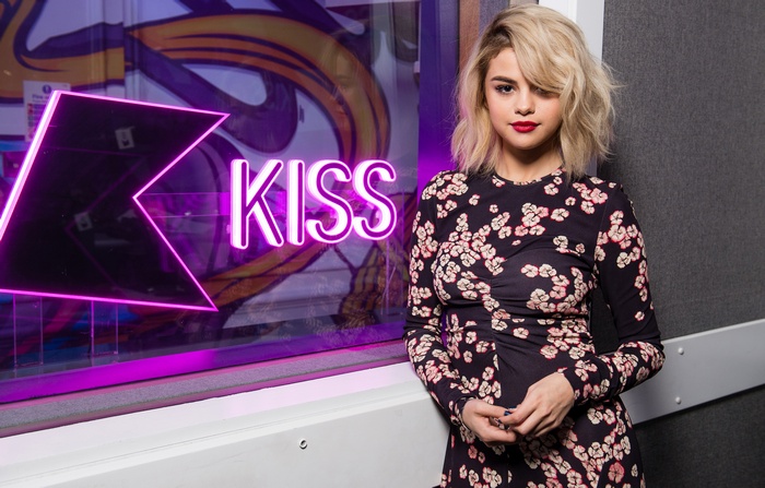Selena Gomez in front of KISS neon sign