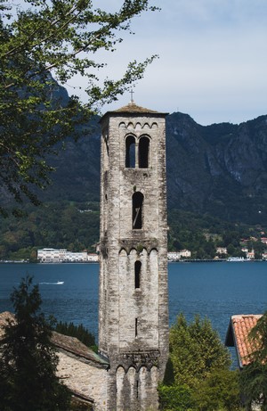 Bell tower by a lake with mountains in the background
