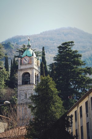 Bell tower with clock and mountains in background