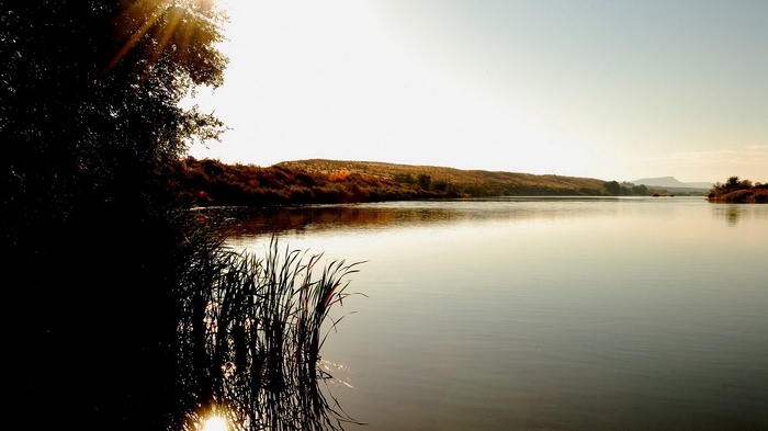 River landscape at sunset with trees and hills