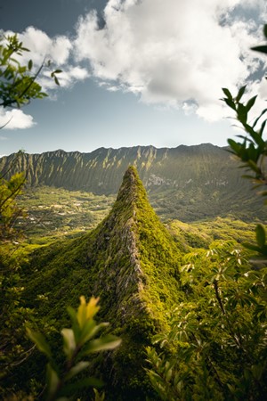 Jagged mountain ridge covered in green trees under a cloudy sky