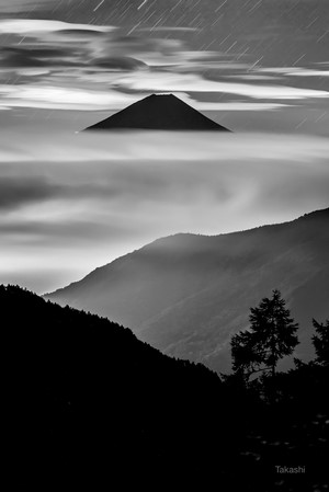 Mount Fuji above clouds with star trails and mountains