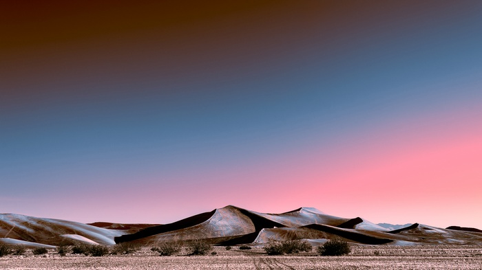 Desert dunes at sunset with neon sky