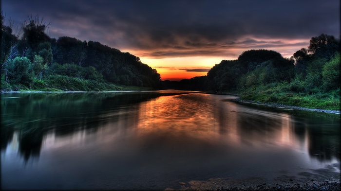 River reflecting sunset through forested hills