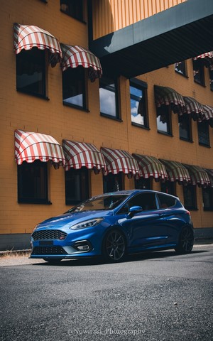 Blue Ford Fiesta ST parked in front of a yellow building
