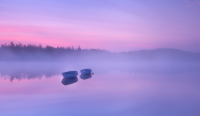 Two rowing boats on a misty lake at sunrise