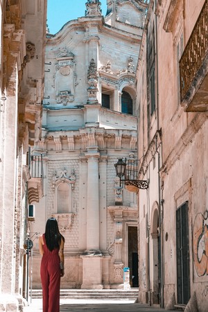 Woman in red jumpsuit in front of Baroque church in Lecce, Italy