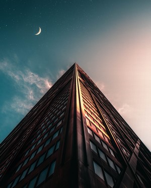 Low-angle view of a skyscraper against the night sky with moon and stars