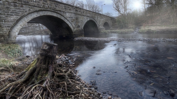 Stone bridge over a river with a tree stump
