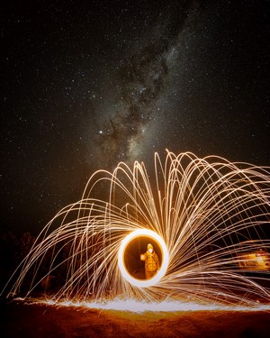 Person performing steel wool light painting under the Milky Way in Tasmania