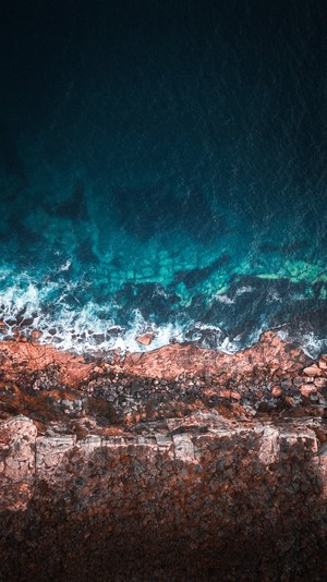 Aerial view of ocean waves crashing on rocky shore