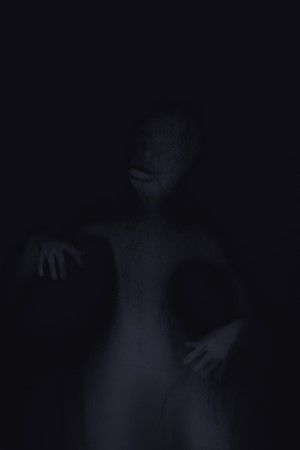 A shadowy figure with hands outstretched in the dark