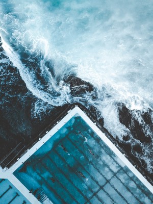 Aerial view of ocean waves crashing into a swimming pool