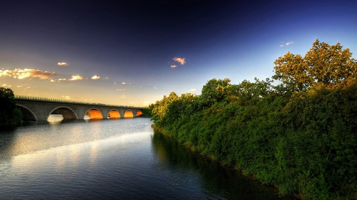 Bridge over river at sunset with trees