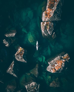 Kayaker navigating through rocky turquoise water