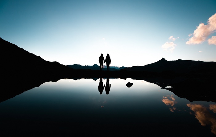Couple holding hands by a lake at sunset