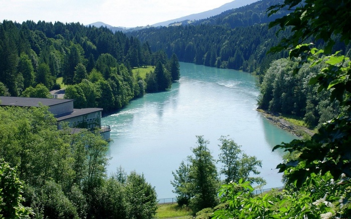 River flowing through a forested valley with a building