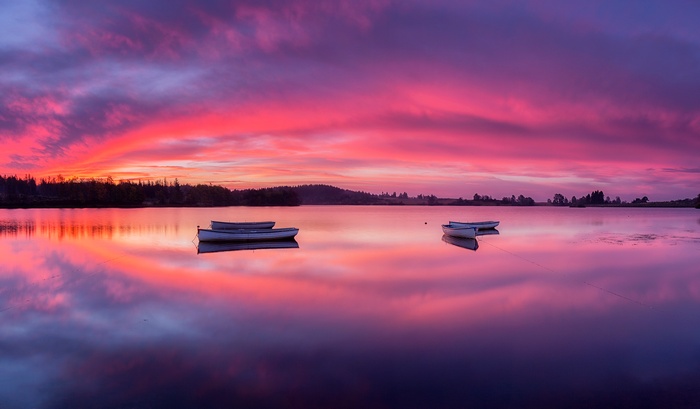 Rowing boats on a lake at sunrise with colorful sky