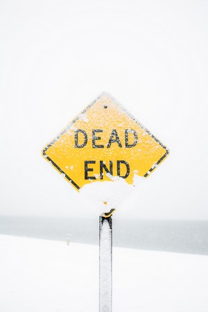 Yellow dead end road sign covered in snow