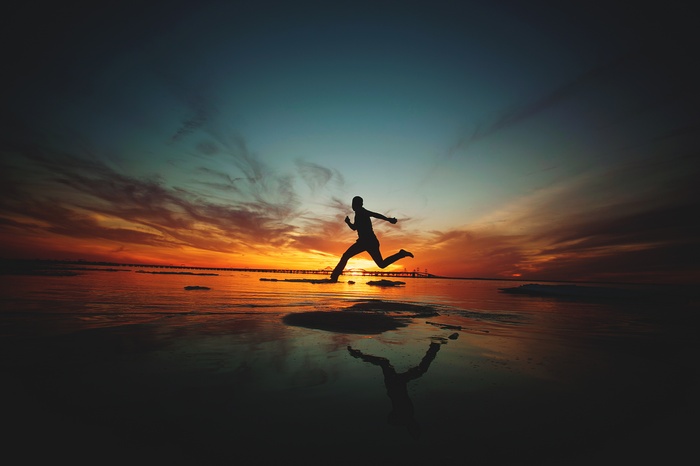 Silhouette of a person running at sunset on a beach