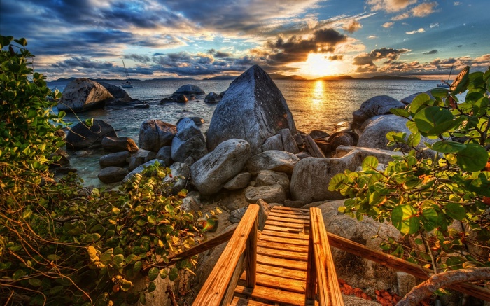 Wooden walkway to rocky beach at sunset