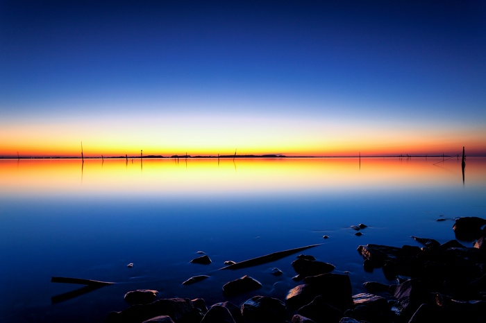 Sunset over a calm lake with rocks in the foreground