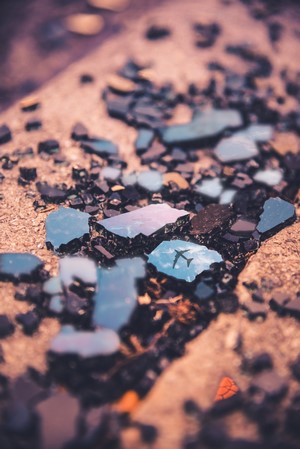 Broken glass reflecting an airplane in the sky